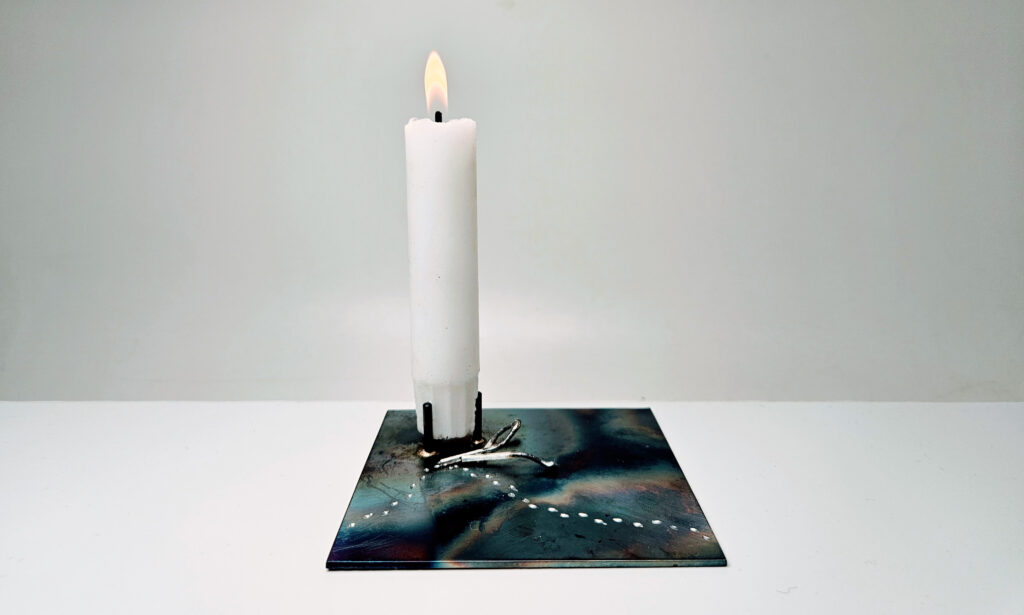 Anna Nordströms ljusstake "Knytt" tillverkad av  järn och silver berättar en historia där spåren i snön får en att känna närvaron av den som kilat förbi. 